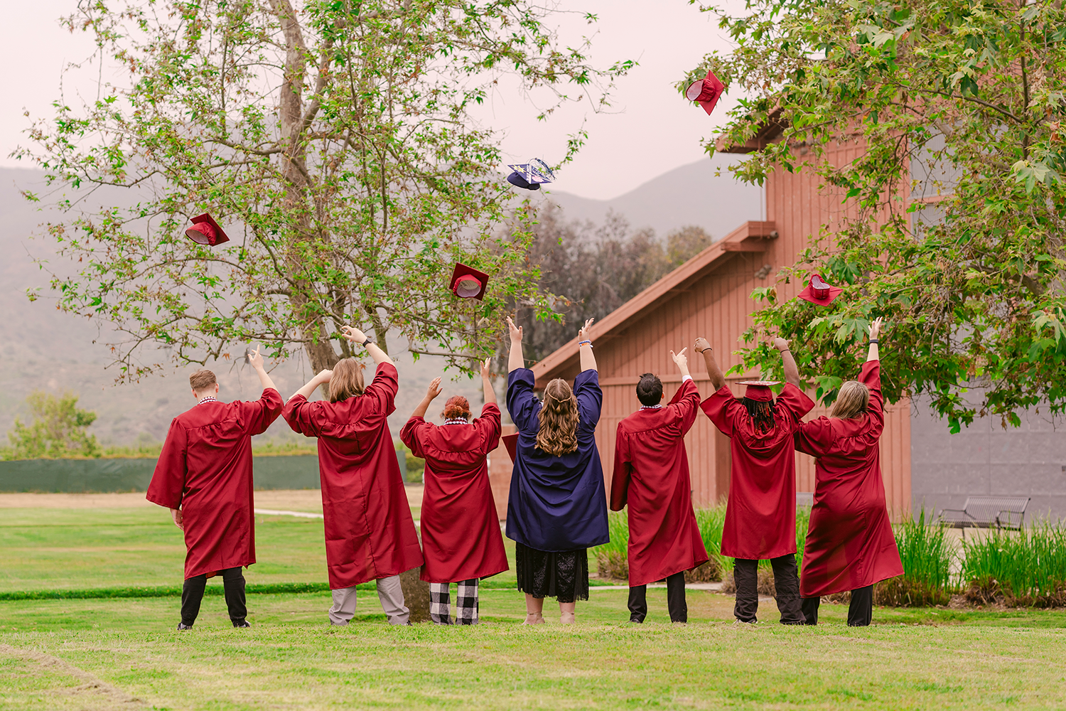 Graduates from Casa Pacifica's non-public school throw their caps into the air.