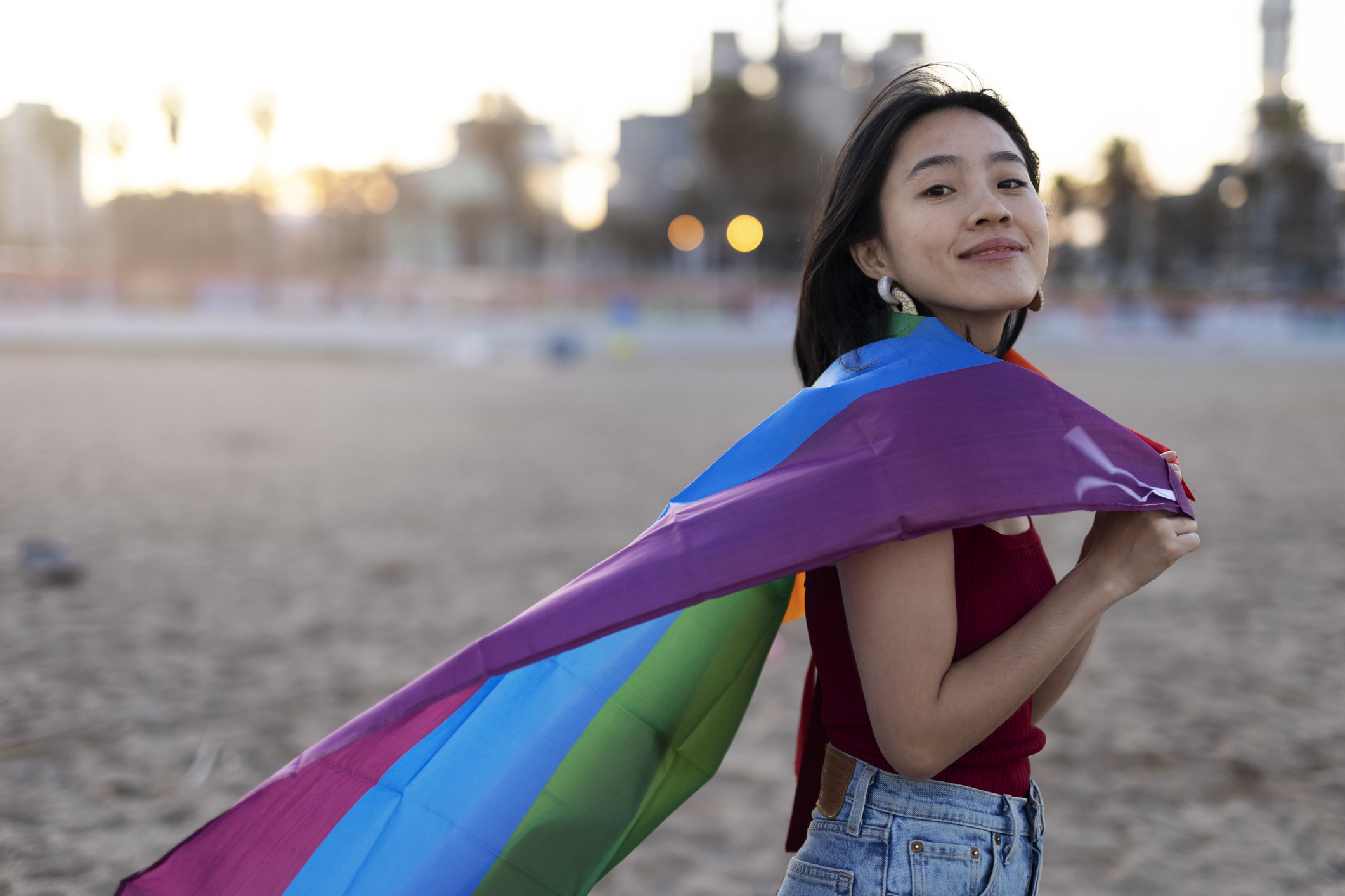 Happy girl with a pride flag at the beach.