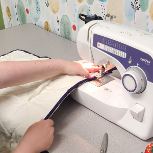 Casa Pacifica youth uses a sewing machine to create a saddle pad.