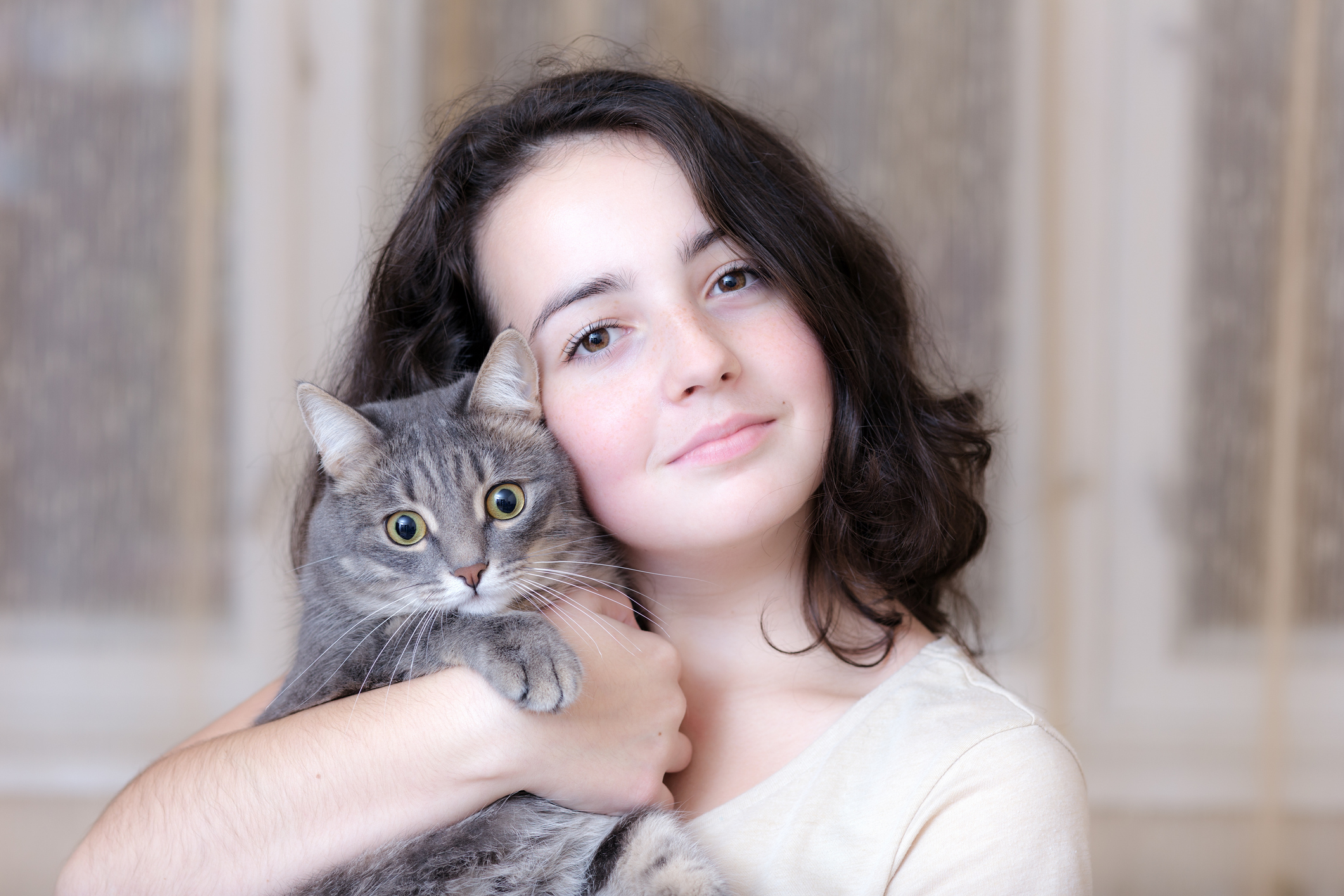 Young girl holding a cat year her head